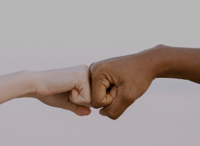 2 handen van diverse etniciteit geven een vuistje; symbool voor Laurastars inzet voor gelijkheid en diversiteit op het werk.